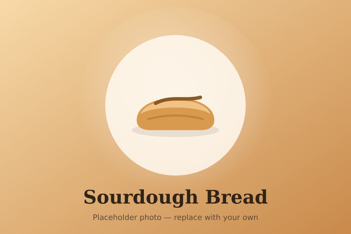 A round loaf of sourdough bread with a deep golden crust and a scored ear, sliced to show an open crumb